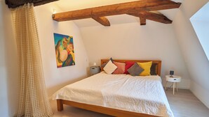 Une chambre à coucher avec un lit en bois, une table de chevet, une lampe et un tableau accroché au mur.
