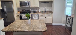 A kitchen with granite countertops, stainless steel appliances, and a central island with a vase of flowers.