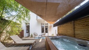 Una terraza de madera con jacuzzi, sillas de descanso y un área de estar cubierta.