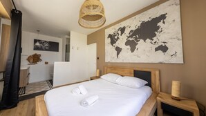 Una habitación de hotel moderna con una cama grande, un mapa del mundo en la pared y un cabecero de madera.