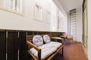 A room with a wooden bench, a small table, a wicker chair, and a ladder against the wall. - Modern Central 4+1 Bedroom Haven (Lisbon)