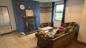 Un salon avec une cheminée, un canapé, une petite table et une fenêtre avec des rideaux.