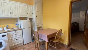 Une cuisine de taille réduite avec des meubles blancs, une table et des chaises.