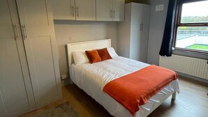 Une chambre à coucher avec un lit, des armoires blanches, une fenêtre donnant sur un beau paysage et un luminaire au plafond.