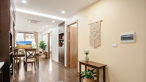 Un pasillo moderno con suelo de madera, una zona de comedor con mesa y sillas, y una sala de estar con televisor.