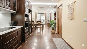 Una cocina moderna con armarios de madera oscura, horno empotrado y comedor con mesa y sillas.
