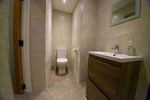Kylpyhuone, jossa on wc, pesuallas ja peili.