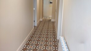 A hallway with patterned tile flooring, white walls, and a radiator on the right. - The Oyster House (Clarinbridge)