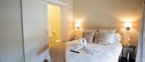 Una habitación de hotel con cama, mesitas de noche, lámpara e instalación artística con toallas.
