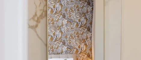 Ein Badezimmer mit Marmorwaschbecken, einem Spiegel und blumigem Wandpapier.