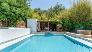 Una piscina con solárium y una zona de estar cubierta.