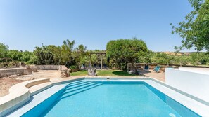A swimming pool with a wooden deck, lounge chairs, and a pergola. - Monte Solteiras III in Tavira by Lovelystay (Conceição)