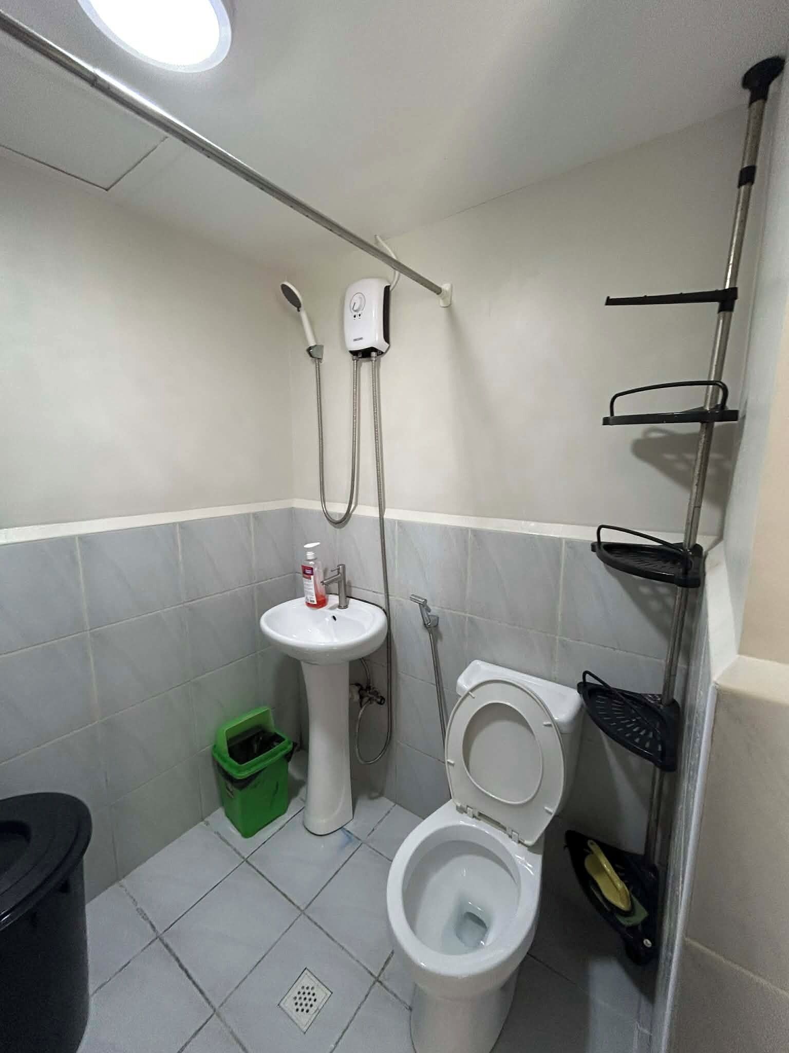 A small bathroom with a toilet, sink, and shower.