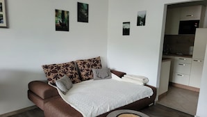 A modern living room with a brown sofa, white throw, and a small round table.