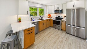 Une cuisine moderne avec des armoires blanches, des appareils en acier inoxydable et un plan de travail en bois.