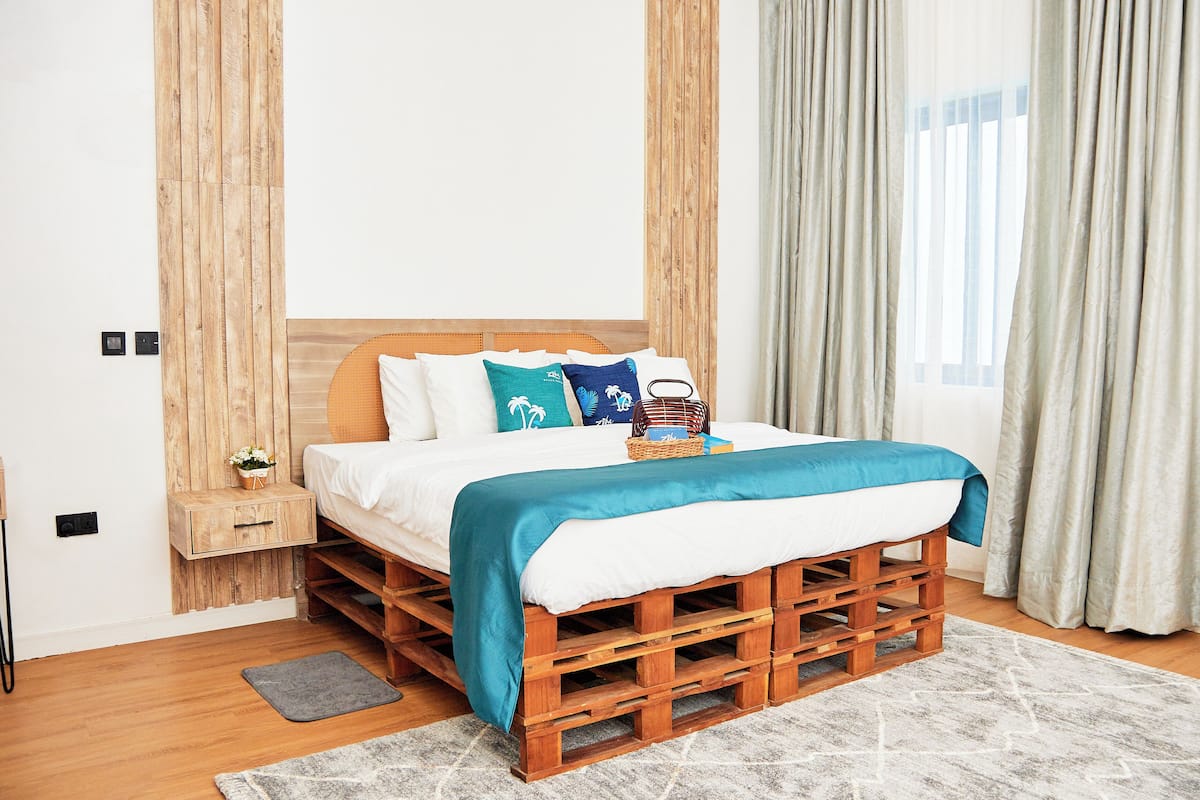 A bedroom with a wooden pallet bed, white bedding, and a teal throw blanket.