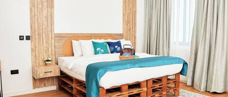 A bedroom with a wooden pallet bed, white bedding, and a teal throw blanket.