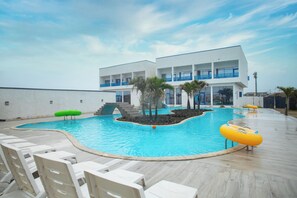 A swimming pool with lounge chairs, a building with balconies, and palm trees. - Ziba Beach Resort  (Lekki)