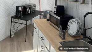 Een kleine keuken met een koffiezetapparaat, broodrooster, magnetron en afwasschaal.