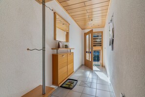 A hallway with a wooden cabinet, a mirror, and a door leading to a balcony.