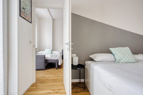 A modern bedroom with a large bed, a smaller bed, and a desk. - Elegant apartments in Isola district (Milan)