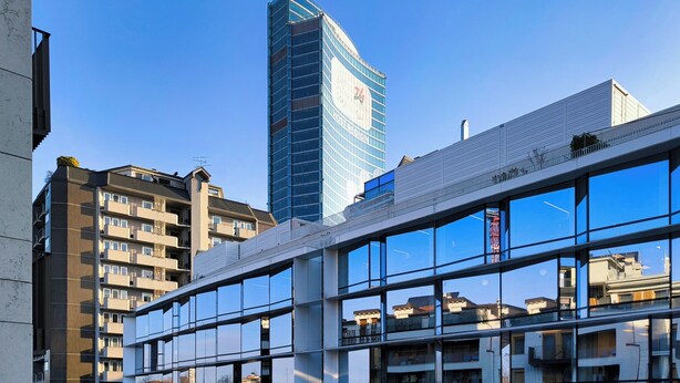 Un bâtiment moderne doté de grandes fenêtres et d’une façade en verre, entouré d’autres immeubles.