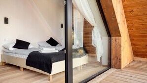 Een moderne slaapkamer met een bed, witte lakens en een zwart plaid.