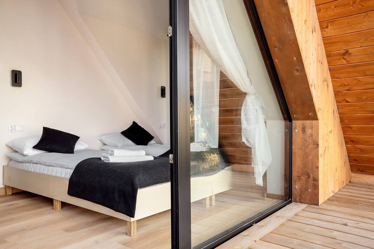 Une chambre à coucher moderne avec un lit, du linge de lit blanc et un plaid noir.