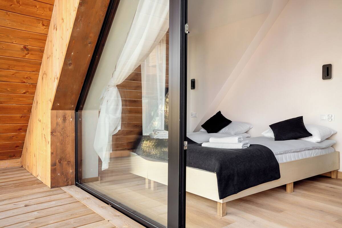 Une chambre à coucher avec un lit, une fenêtre ornée de rideaux légers et un plafond en bois.