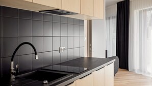 Een moderne keuken met zwarte tegels, een zwarte spoelbak en houten kastjes.