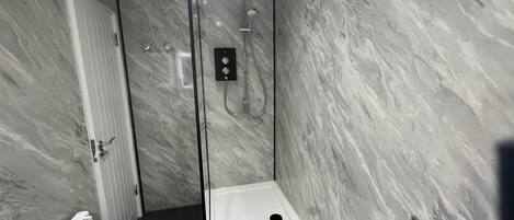 Une salle de bain moderne avec une douche en verre, des murs en marbre et un lavabo blanc.