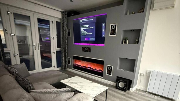 A modern living room with a grey sofa, a coffee table, a flat-screen TV mounted on the wall, and a fireplace below the TV. - Private 2 Bedroom Apartment -edinburgh - Sleeps 4 (Edinburgh)