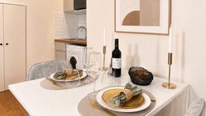 Un comedor con una mesa dispuesta para dos personas, una botella de vino, copas y una obra de arte abstracta enmarcada en la pared.