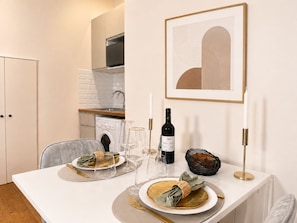 A dining area with a table set for two, a bottle of wine, glasses, and a framed abstract artwork on the wall. - 2063 Lille (Paris)