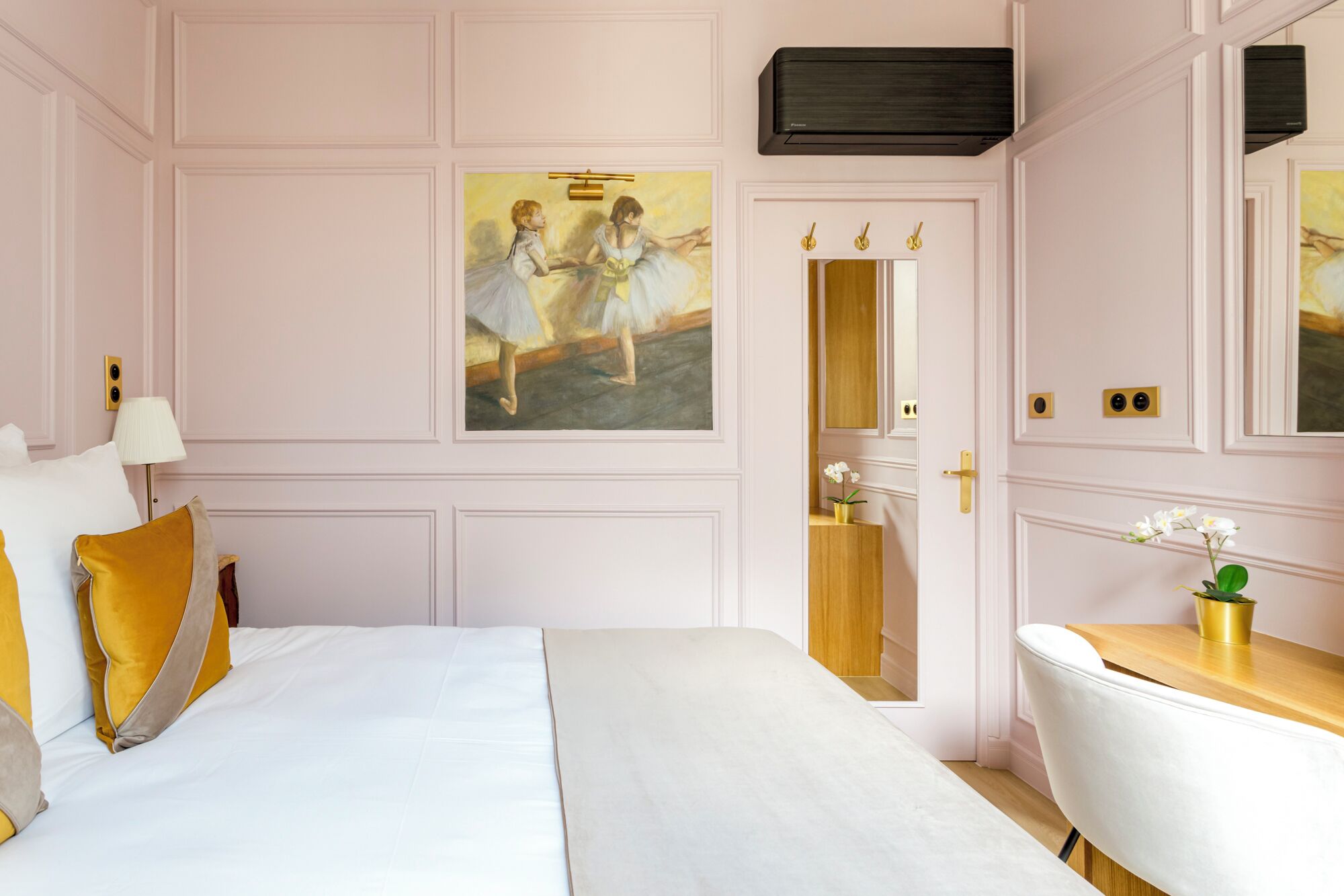 A hotel room with a large bed, a desk, and a painting of ballerinas on the wall.
