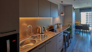 A modern kitchen with stainless steel appliances, a wooden countertop, and a dining area with a view of the city. - Student Only Cumberland Place (Southampton)