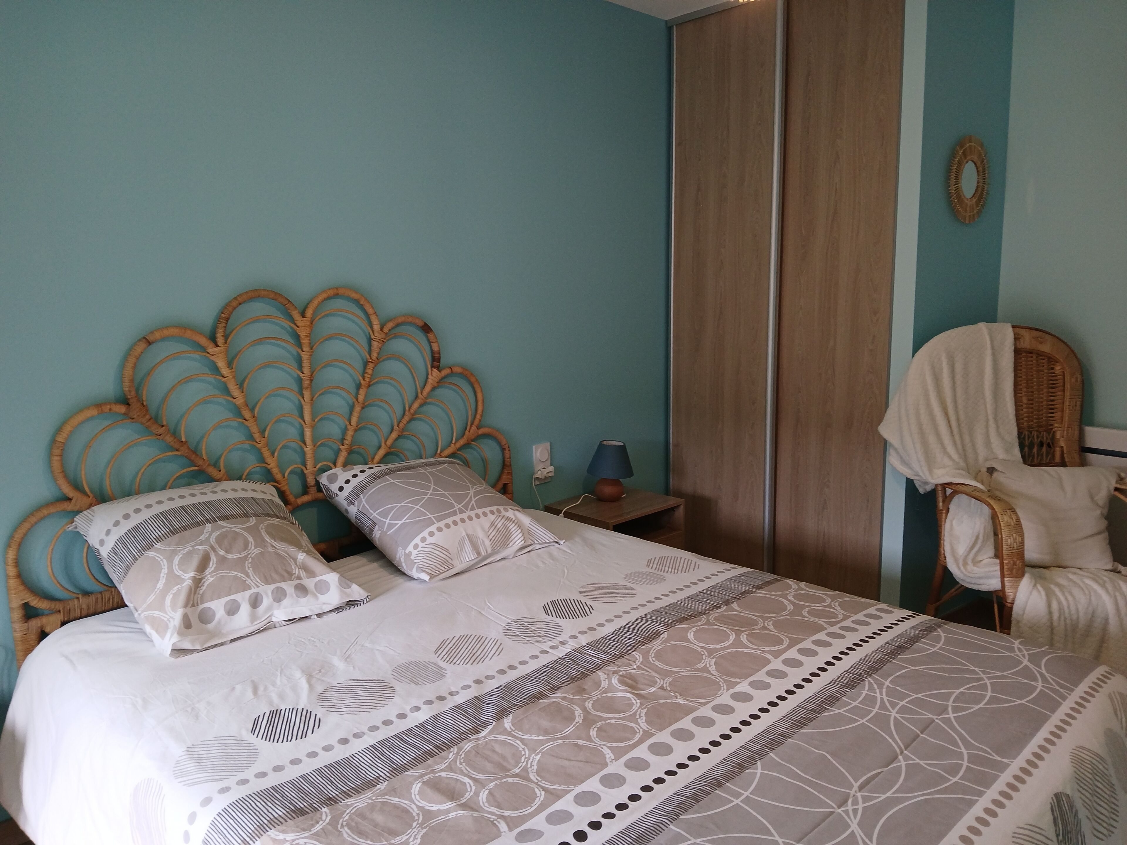 A bedroom with a bed, a nightstand, a chair, and a wardrobe.