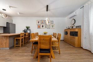 A modern kitchen with a dining area, wooden furniture, and wall-mounted artwork. - Villa Rosea Domus ZadarVillas (Podlug)