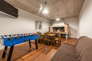 A cozy living room with a foosball table, a brick fireplace, and a television mounted on the wall. - Villa Rosea Domus ZadarVillas (Podlug)