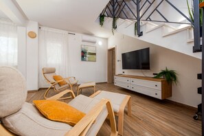 A modern living room with a sofa, a TV, and a staircase. - Villa Rosea Domus ZadarVillas (Podlug)