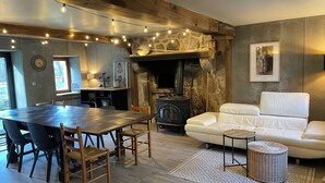 A cozy living room with a fireplace, a dining area with a wooden table and chairs, and a white sofa.