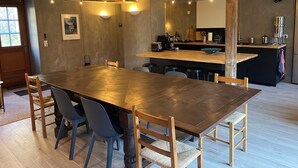 A dining area with a long wooden table, several chairs, and string lights.