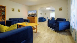 A spacious living area with blue sofas, a wooden coffee table, and a television on a wooden cabinet. - The vacation apartment in Sigmaringen (Sigmaringen)