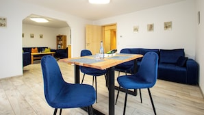 A dining area with a wooden table and four blue chairs, a blue sofa, and a wooden cabinet in the background. - The vacation apartment in Sigmaringen (Sigmaringen)