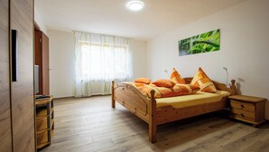 A bedroom with a wooden bed, a nightstand, a wooden wardrobe, and a window with curtains. - New vacation apartment in Sigmaringen, 15 minutes' walk to the pedestrian zone. (Sigmaringen)