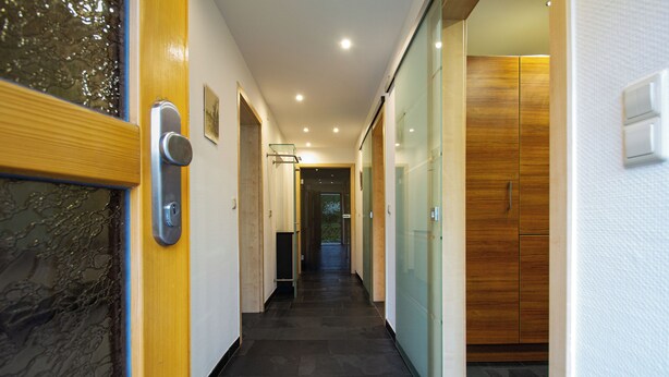 A hallway with a wooden door, a glass partition, and a wooden wardrobe. - New vacation apartment in Sigmaringen, 15 minutes' walk to the pedestrian zone. (Sigmaringen)