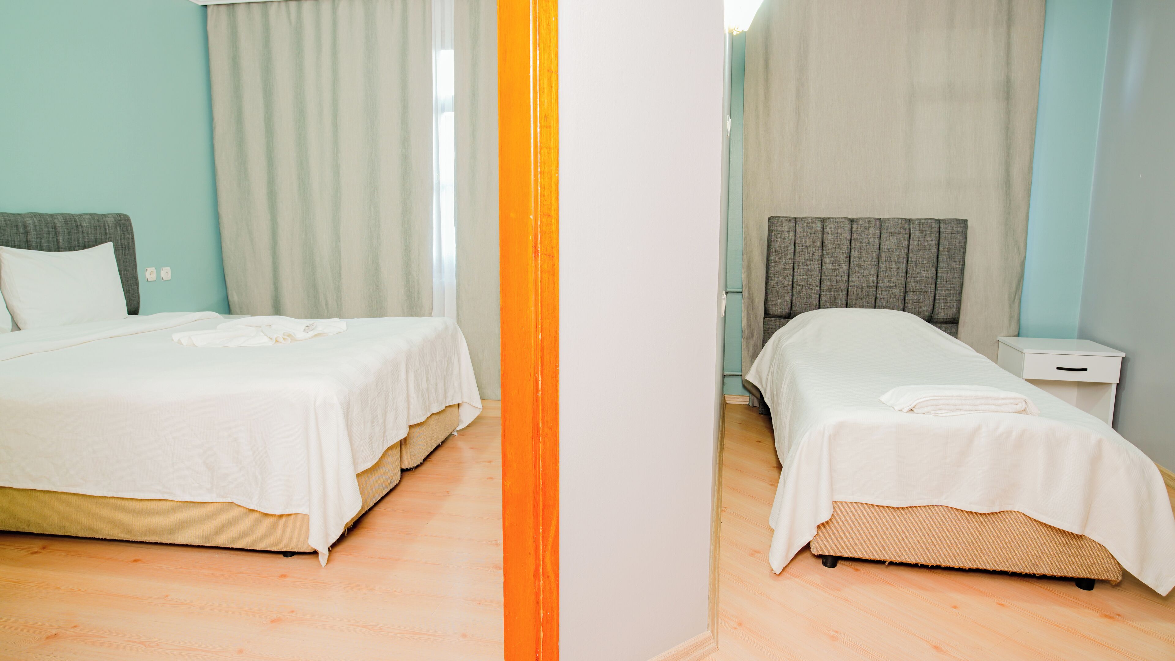 A hotel room with two beds, a nightstand, and a mirror.