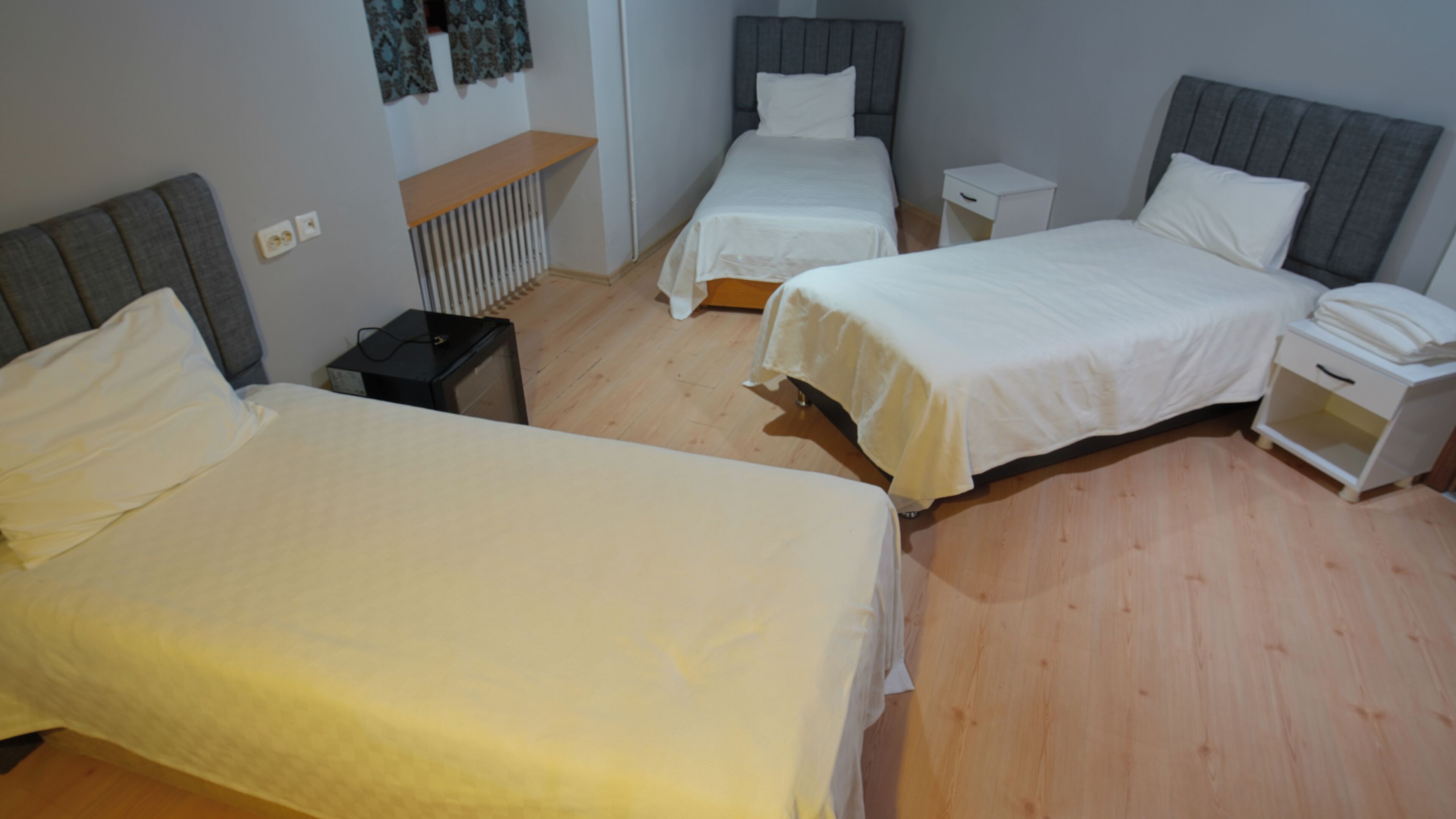 A room with two single beds, a bedside table with a lamp, and a small cabinet.