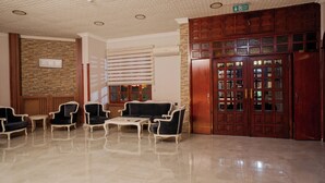 Um hall com área de estar, lareira e uma grande porta de madeira.