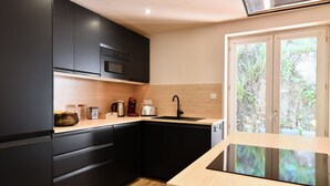 Een moderne keuken met zwarte kastjes, een houten aanrechtblad en een inbouwfornuis.